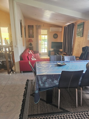A dining area with a table, chairs, a red sofa, and a television.