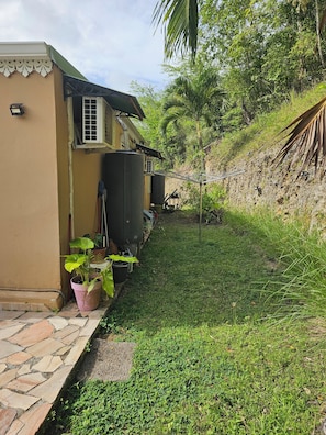 A house with a paved entrance, a small garden, and a water tank.
