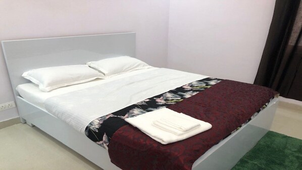 Un lit avec une literie blanche et une couverture à motifs floraux.