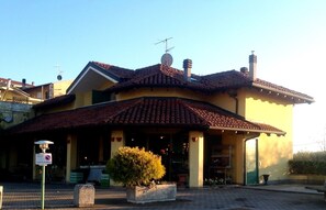 A two-story building with a tiled roof, a satellite dish, and a small garden area with a potted plant. - At the number in Viverone (Viverone)