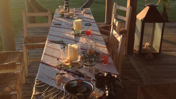 A wooden deck with a table set for a meal, overlooking a grassy field. - Beach House facing the sea in dreaming Estancia (Punta del Este)