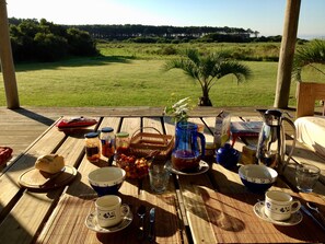A picnic setup on a wooden deck with a view of a grassy field and trees. - Beach House facing the sea in dreaming Estancia (Punta del Este)