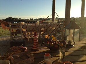 A wooden deck with a table set for dining, featuring a striped lighthouse decoration, a lantern, and a bowl of fruit. - Beach House facing the sea in dreaming Estancia (Punta del Este)