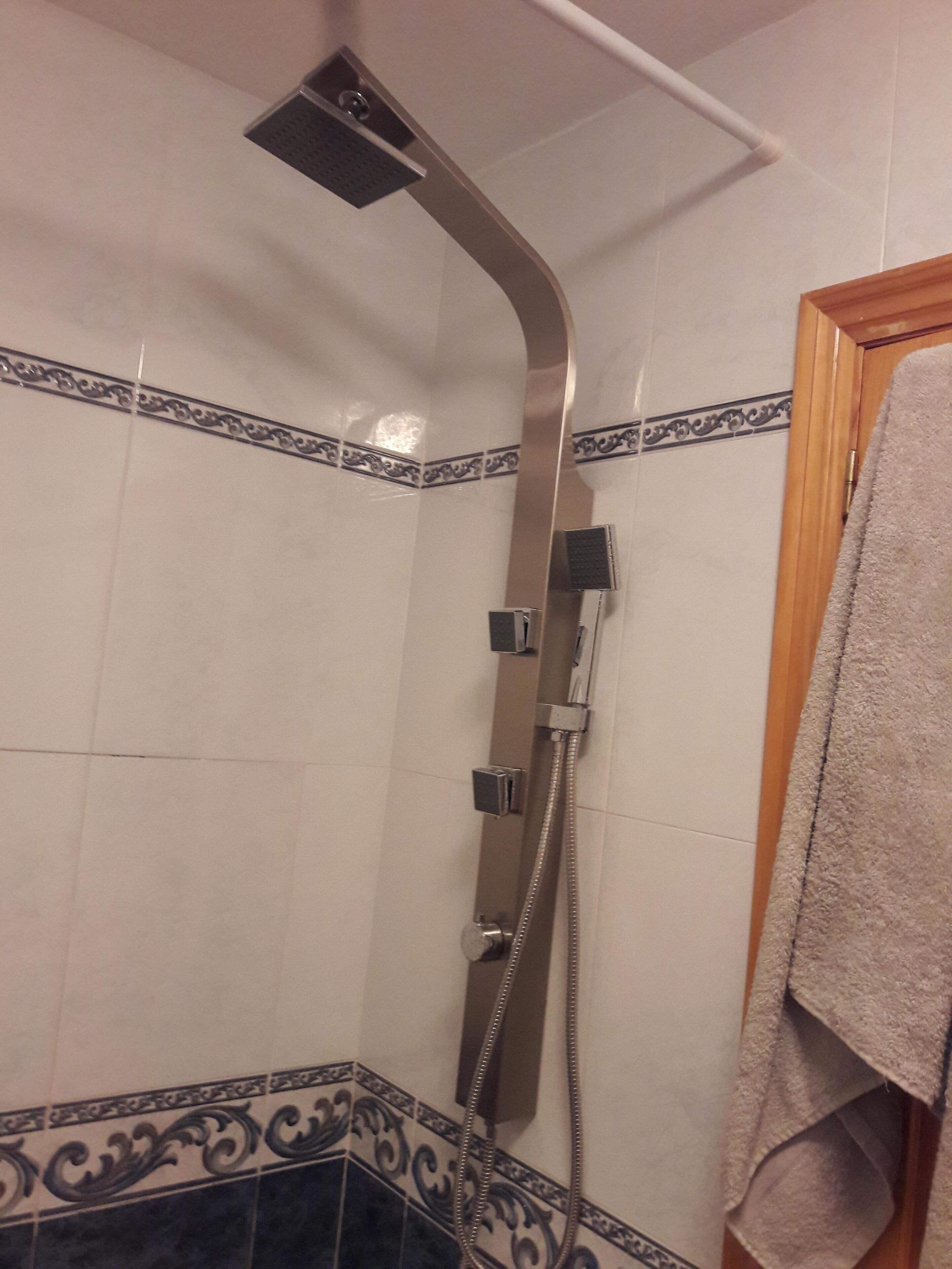 A shower with a curved design, a towel rack, and decorative tiles.