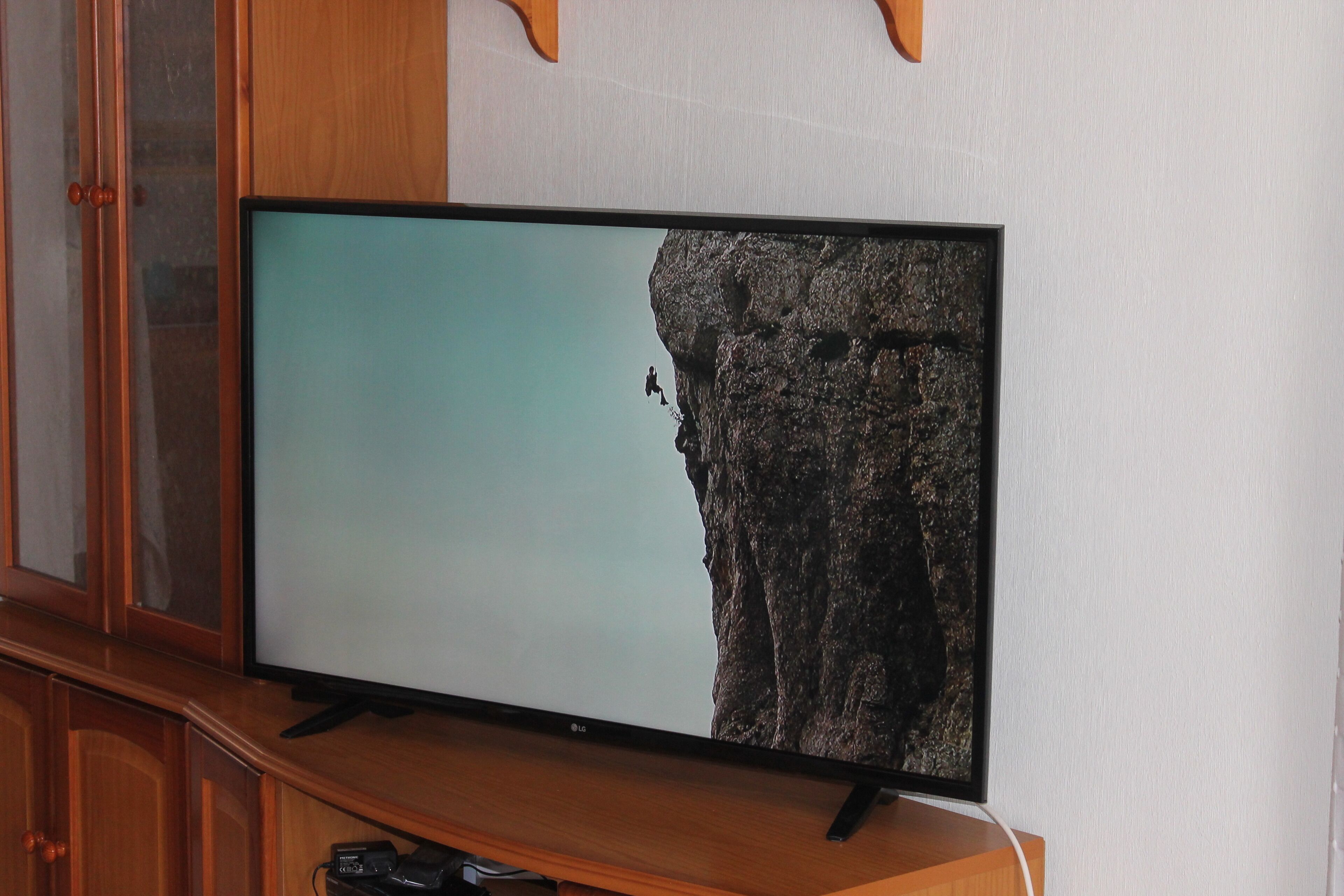Un televisor de pantalla plana sobre un soporte de madera, adosado a una pared.