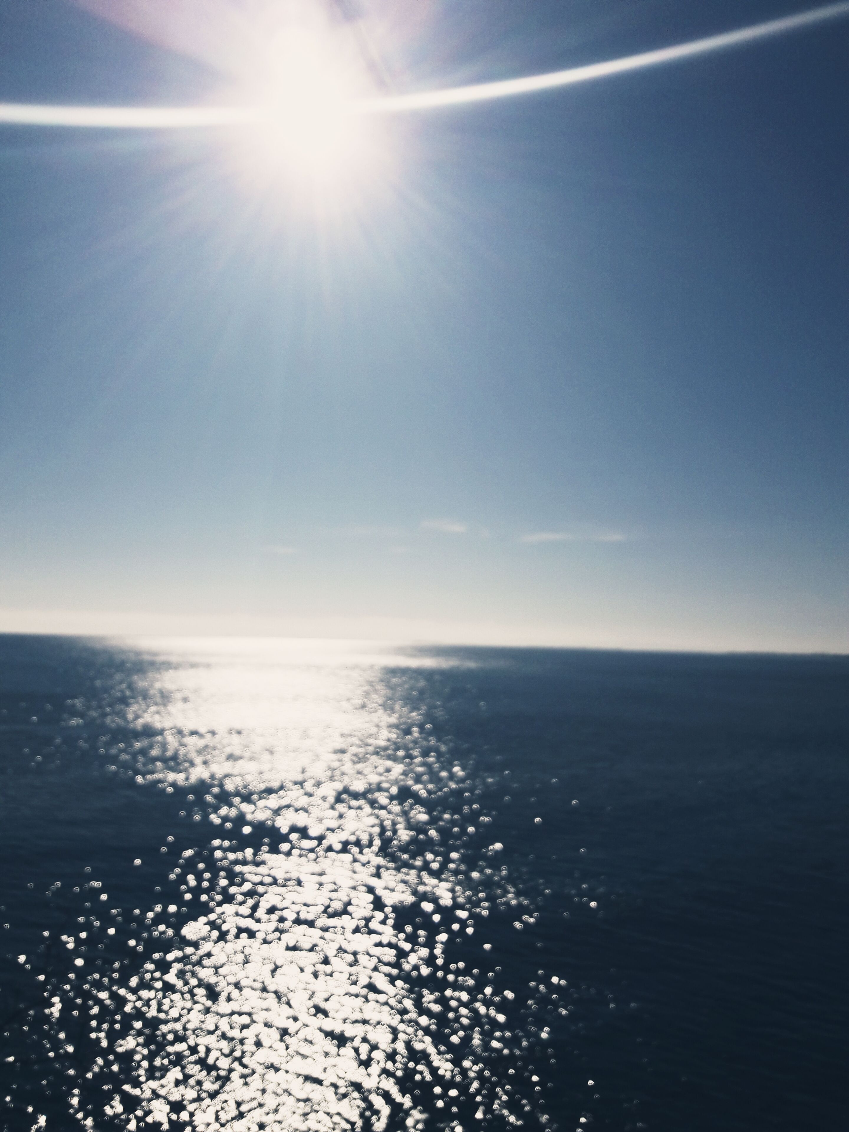 Una vista despejada del océano, con el sol reflejado en la superficie del agua.