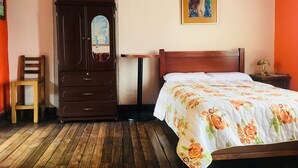 A bedroom with a wooden bed, a wooden wardrobe, a small table, and a chair. - Apartment in Historic Downtown Quito (Quito)
