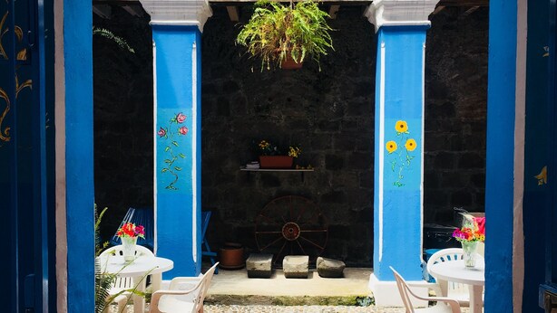 A blue-painted courtyard with a tiled floor, white chairs, and a hanging plant. - Apartment in Historic Downtown Quito (Quito)
