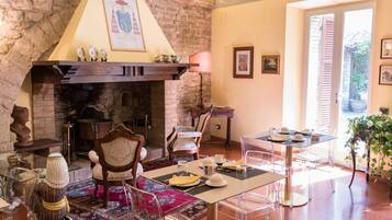 Un comedor con chimenea, sillas traslúcidas, una mesa para dos y vistas al exterior.