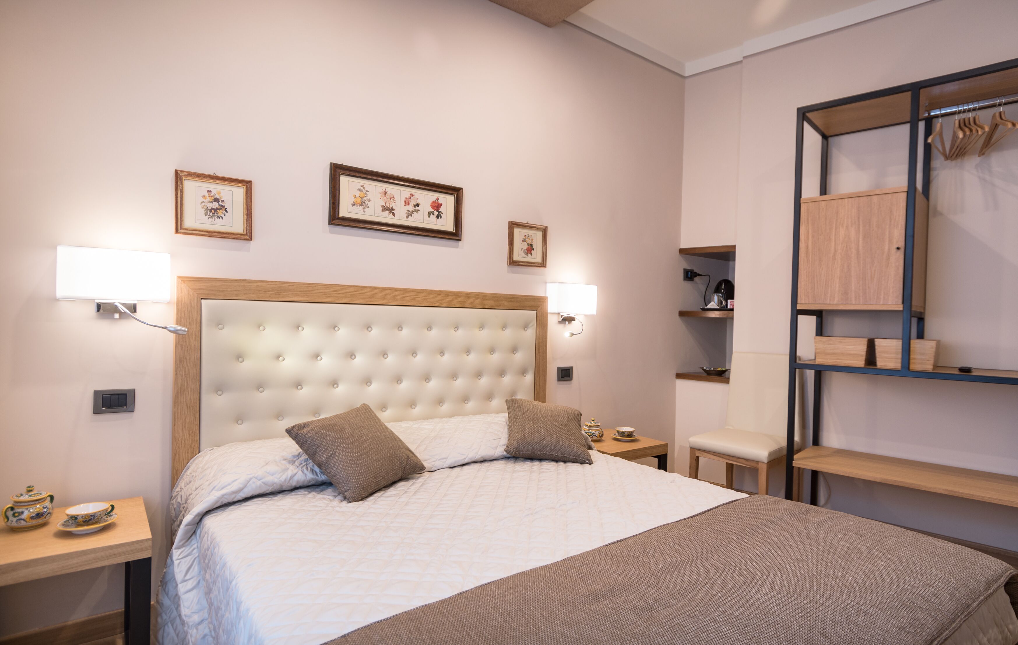 A neatly arranged hotel room with a large bed, bedside tables, a wardrobe, and wall-mounted artwork.