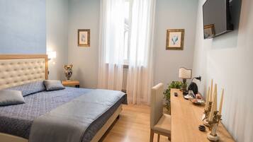 Un dormitorio con cama, mesita de noche, lámpara y televisor montado en la pared.
