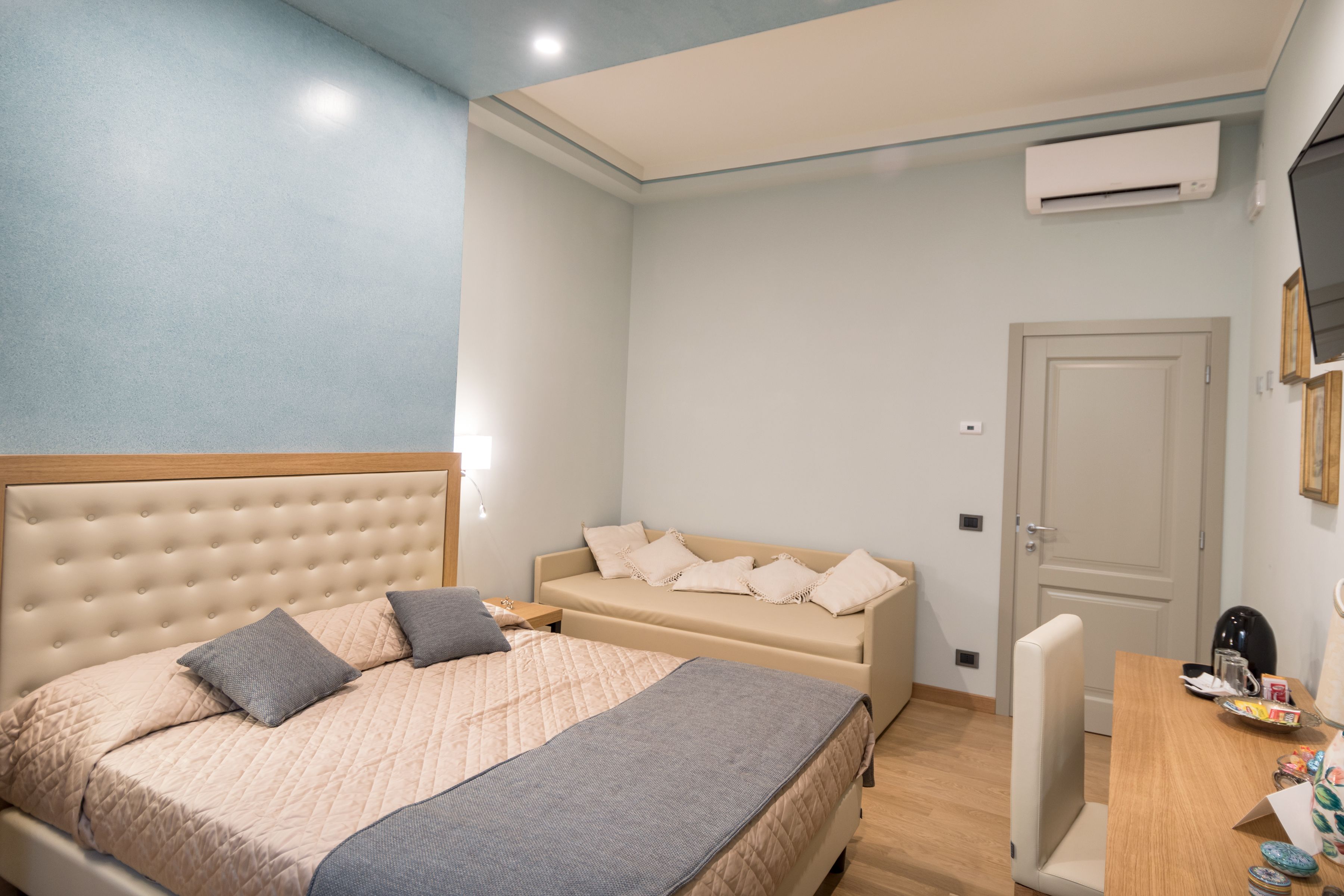 Quarto com cama, sofá, escrivaninha e ar condicionado.