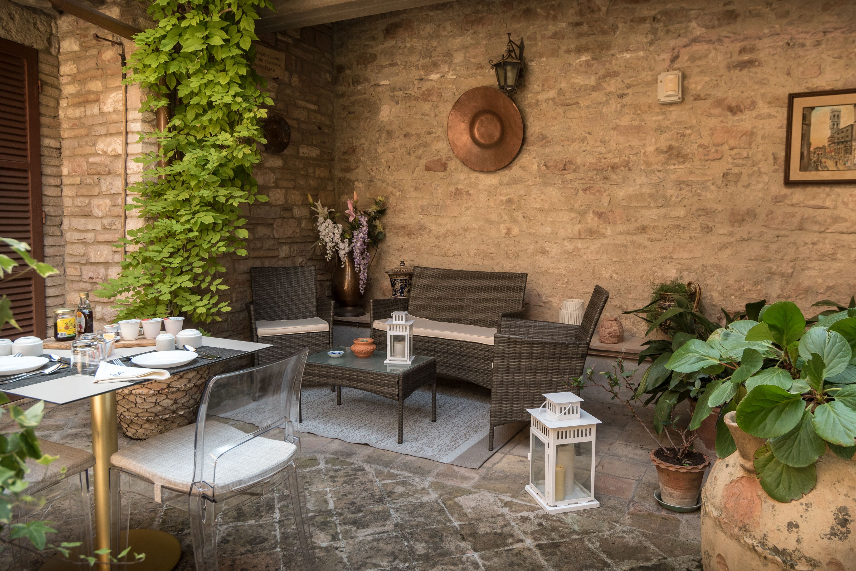 Un espacio al aire libre acogedor con mobiliario de mimbre, una mesa de piedra y plantas en macetas.