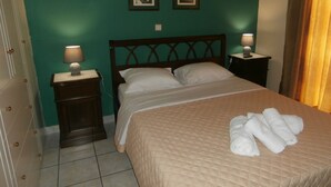 Cama bem arrumada com cobre acolchoado, duas luminárias de cabeceira e um conjunto de toalhas sobre a cama.