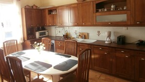 Uma cozinha com armários de madeira, uma mesa de jantar com cadeiras, micro-ondas e cafeteira.