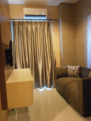 Relax in this stylish living space with a flat-screen TV, comfortable sofa, and air conditioning for a cozy stay.