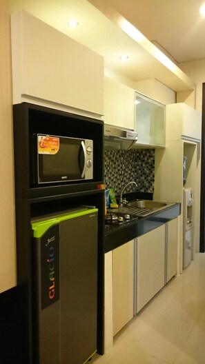 Modern kitchen with microwave, refrigerator, and sink, featuring a minimalist design and clean layout.