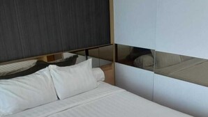 A modern bed with a wooden frame and white bedding. - GP Plaza Apartment (Jakarta)