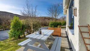 A white wooden picnic table with two benches, a wooden planter box, and a ladder leaning against a white wall. - Cottage 315 -  Clifden - sleeps 4 guests  in 2 bedrooms (Clifden)