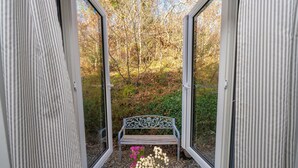 A view through a glass door with a bench and flowers in the foreground. - Cottage 315 -  Clifden - sleeps 4 guests  in 2 bedrooms (Clifden)