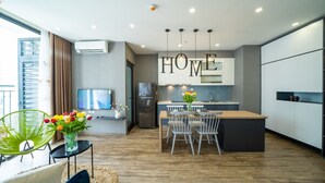 Une cuisine moderne dotée d’un îlot central, d’un coin repas avec des chaises et d’un téléviseur fixé au mur.