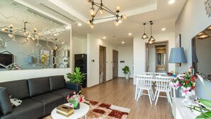 Un salon moderne avec un canapé, une table basse et des plantes décoratives. On y trouve également un coin repas avec une table et des chaises.