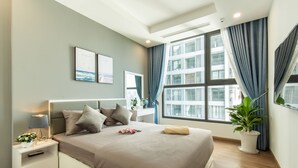Une chambre d’hôtel moderne avec un grand lit, des tables de chevet, une plante en pot et une vue sur la ville grâce à de grandes fenêtres.