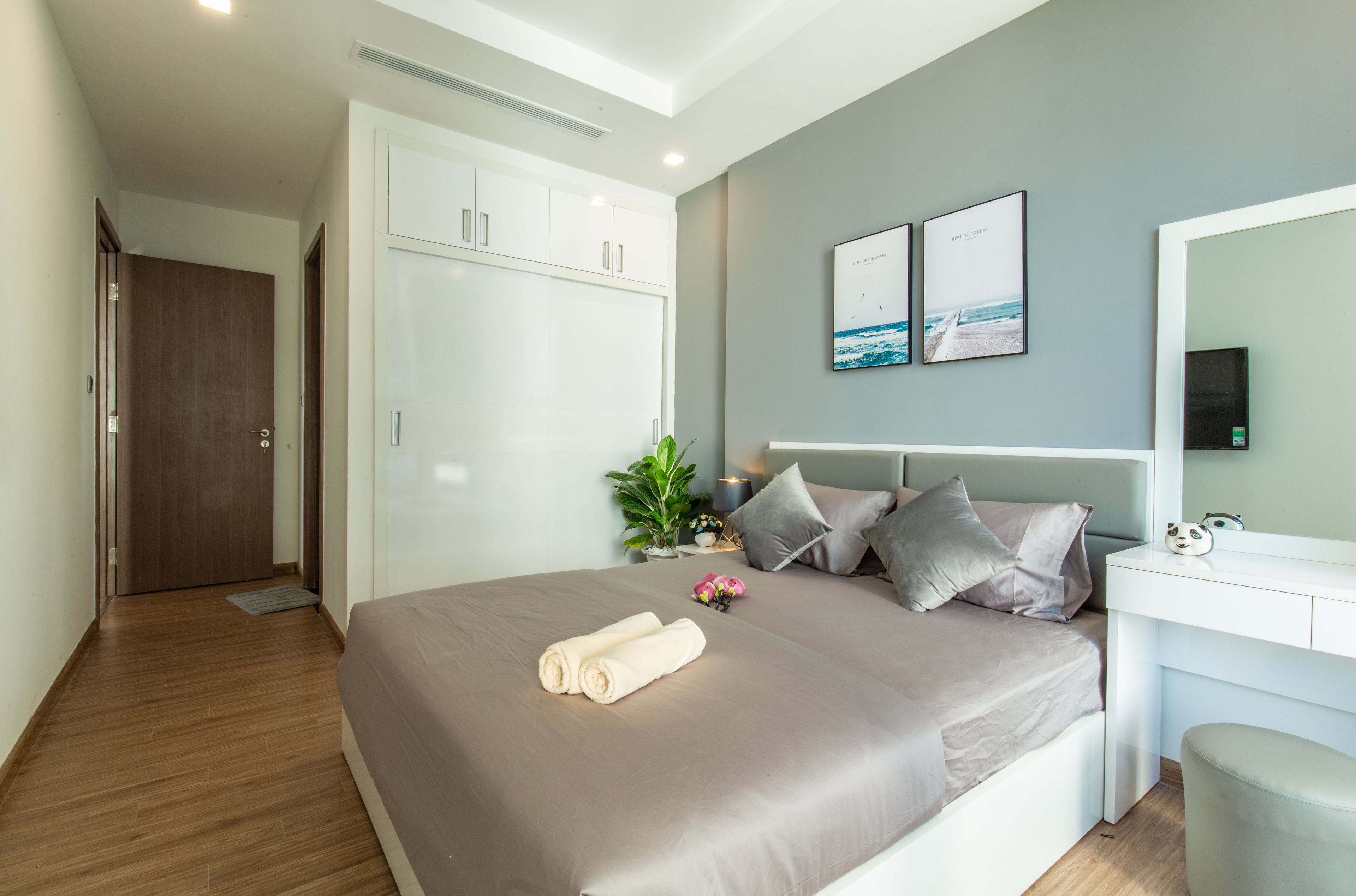 A modern bedroom with a large bed, a desk, and a wardrobe.