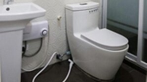 Une salle de bain avec un lavabo blanc, des toilettes et une douche à parois de verre.