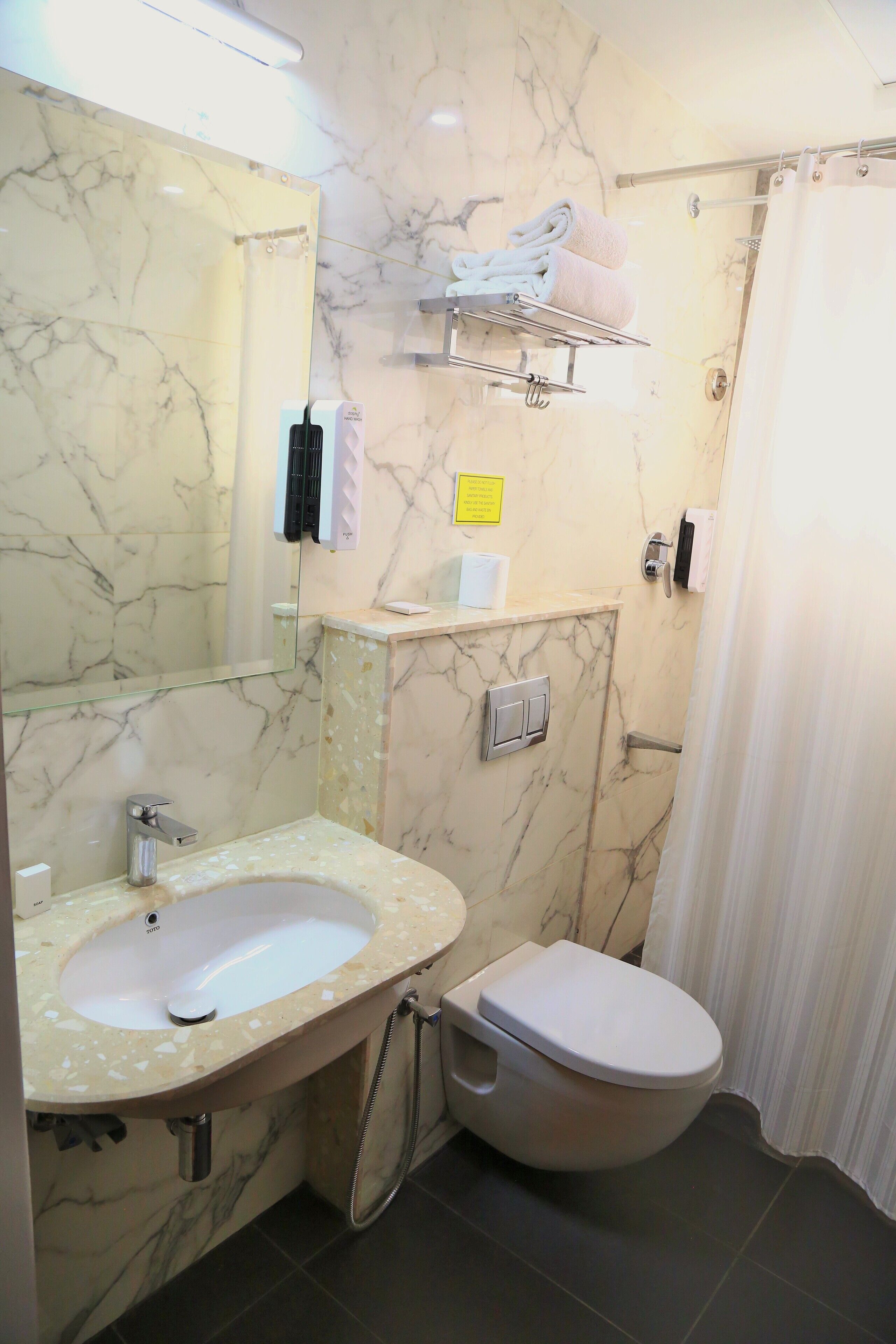 A bathroom with a marble sink, toilet, and shower curtain.