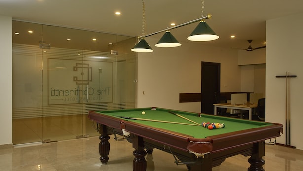 Una mesa de billar en una habitación de hotel con un muro de cristal y un ventilador de techo.