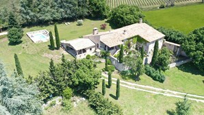 Vue aérienne d’un vaste domaine comprenant une maison principale, une piscine et des jardins environnants.
