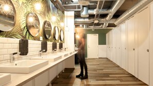 Un baño moderno con varios lavamanos, espejos y casilleros.