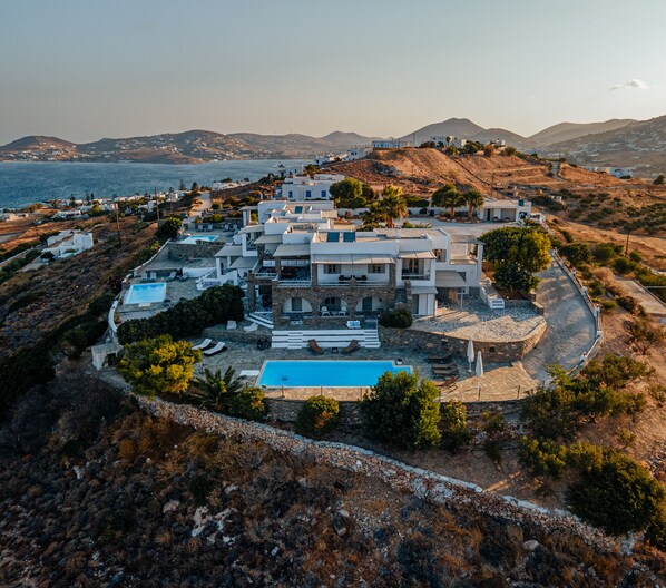 Une vaste villa moderne dotée d’une piscine, entourée d’un paysage rocheux et offrant une vue sur la côte.