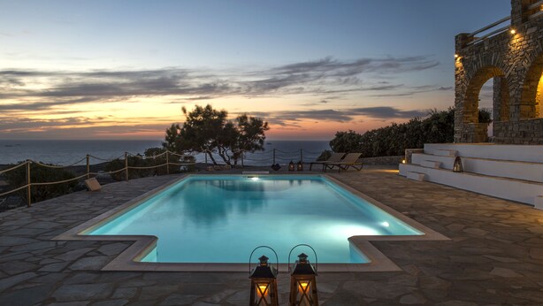 A rectangular swimming pool with a stone deck, two lanterns, and a stone structure with arches. - TERRA retreat in Paros, with prIvate pool, stunning sea view, near sandy beaches (PARIKIA PAROS)