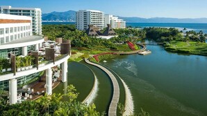 A resort with a river running through it, surrounded by lush greenery and a clear view of the ocean. - Stunning Grand Luxxe 2-Bedroom Loft, Perfect for you to indulge in paradise. (Nuevo Vallarta)