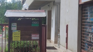 Fachada de edificio con porche cubierto, carteles que indican 'VENDESI' y 'AFFITTASI', y un camino de entrada cerrado con portones.