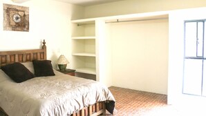 A bedroom with a bed, a nightstand, a lamp, a wooden headboard, a wall decoration, and a closet with a sliding door. - Live like a local in San Cris! Pets welcome! (San Cristóbal de las Casas)