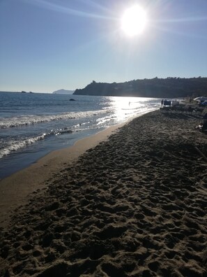 Uma praia com céu limpo e o sol a brilhar.