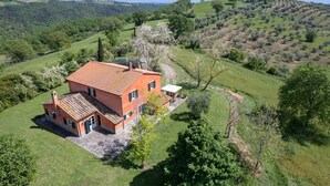 A red-roofed house with a paved patio, surrounded by lush green fields and hills. - House / Villa - Magliano in toscana (Magliano in Toscana)