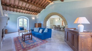 A spacious living room with a blue sofa, wooden coffee table, and a patterned rug. - House / Villa - Magliano in toscana (Magliano in Toscana)
