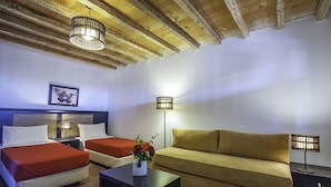 Een hotelkamer met twee bedden, een bank, een salontafel en twee lampen.