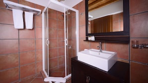 Een badkamer met een witte wastafel, een spiegel en een douche met een glazen deur.