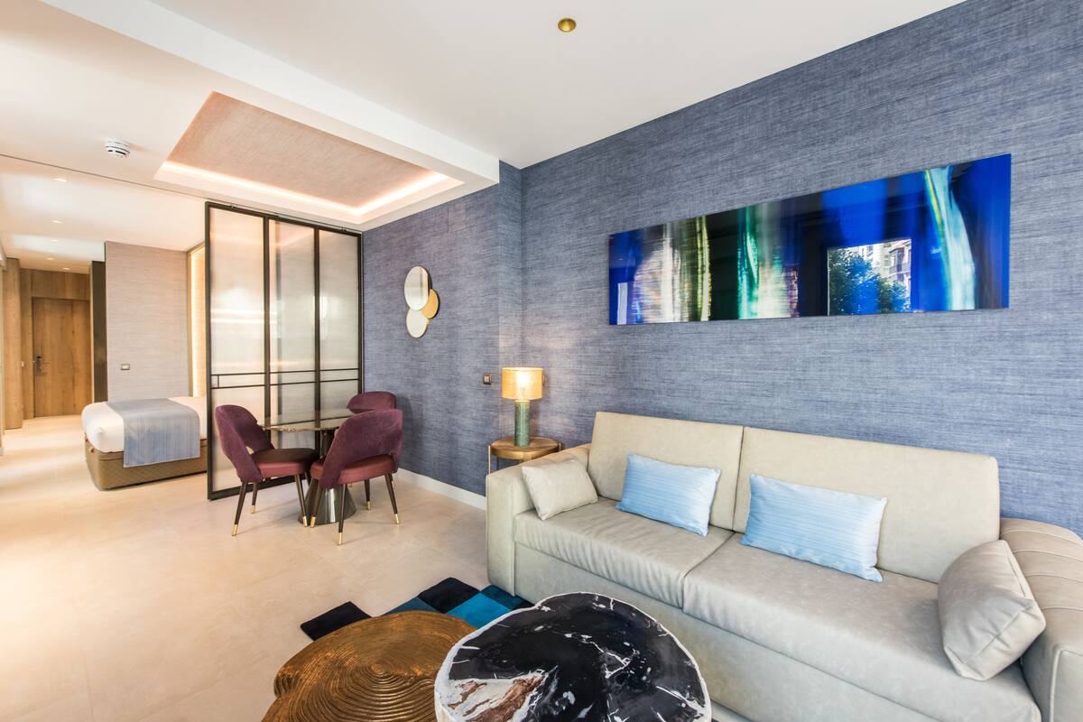 Una sala de estar moderna con sofá, sillones, una mesa de centro y un cuadro en la pared sobre la televisión.