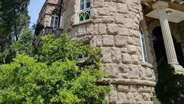 Une tour en pierre, dotée de fenêtres en arc de cercle et d’un balcon.