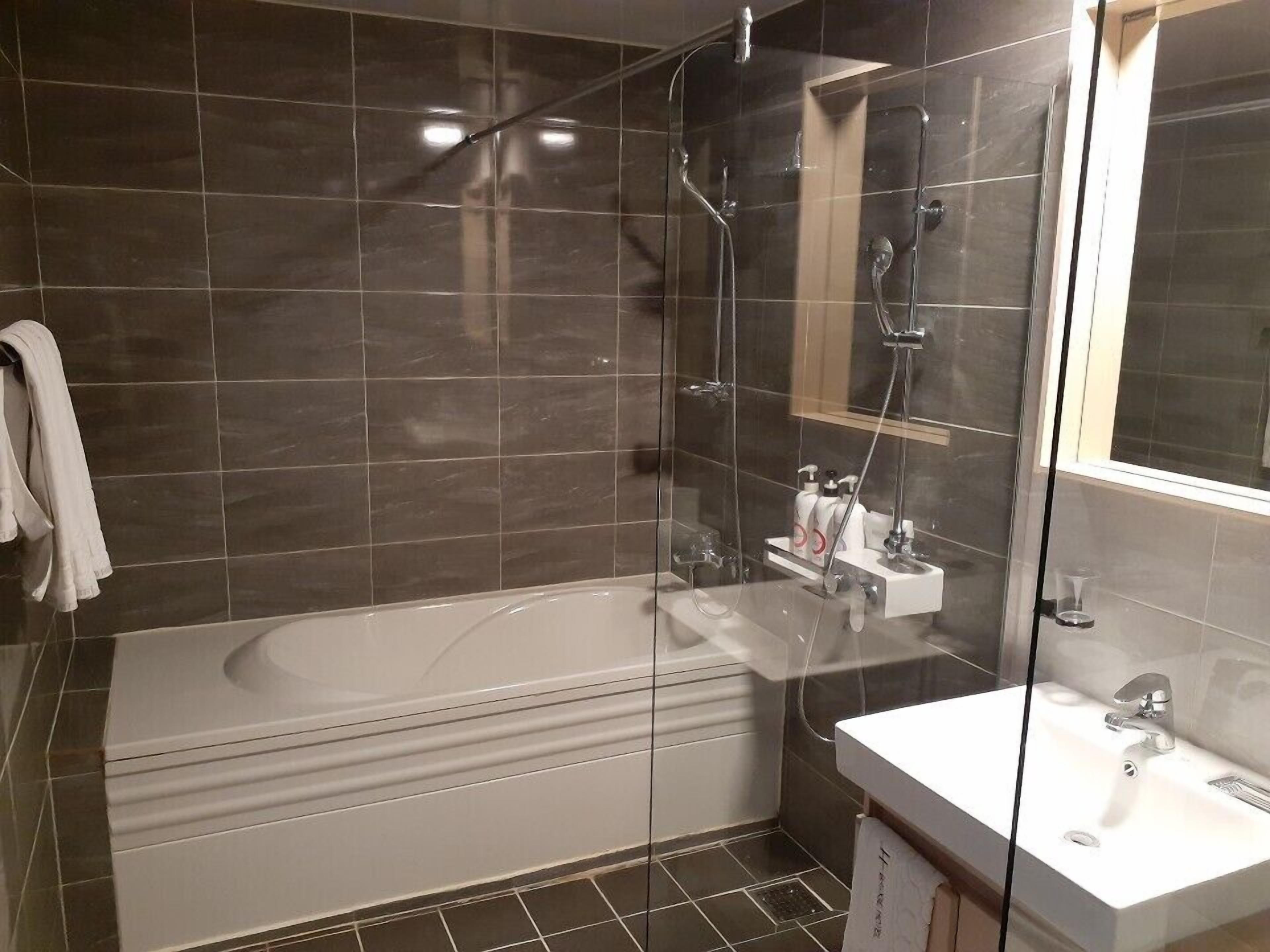 Un baño moderno con ducha de vidrio, una bañera independiente y un tocador con lavamanos.