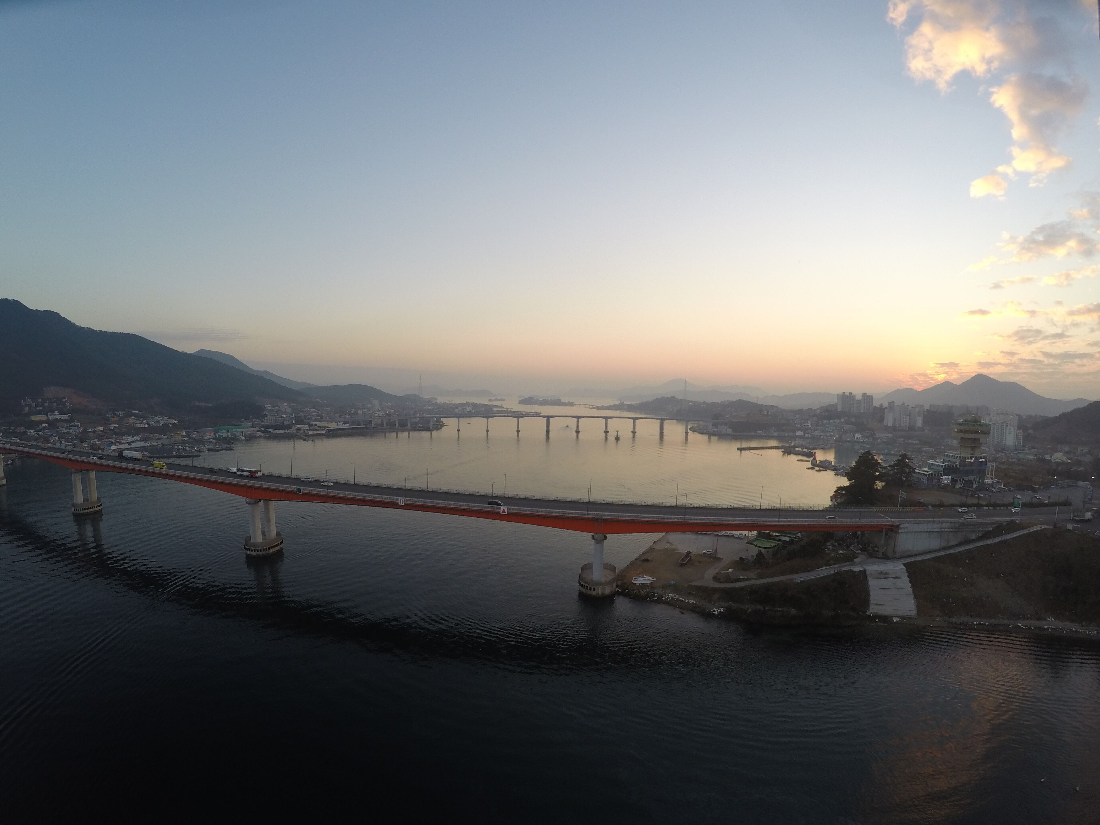 Un puente cruza un río ancho con un paisaje urbano al fondo.