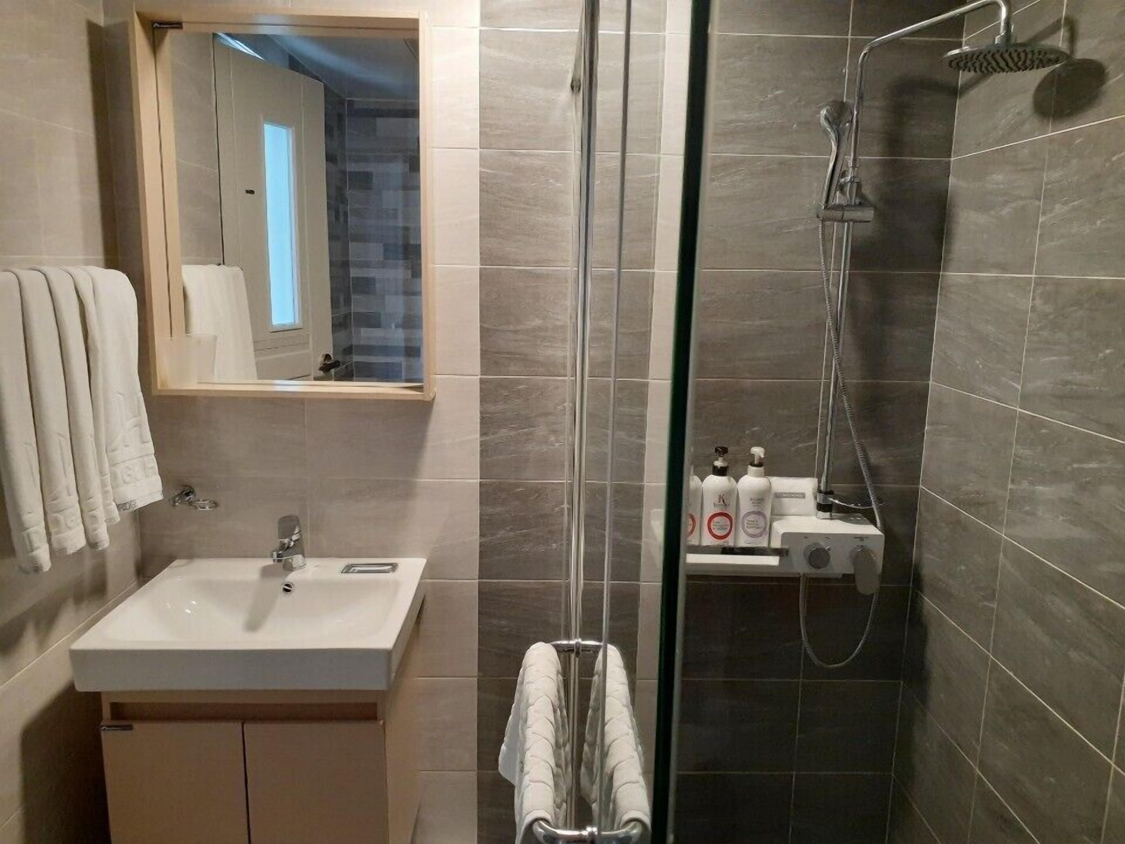 A modern bathroom with a sink, mirror, and shower.
