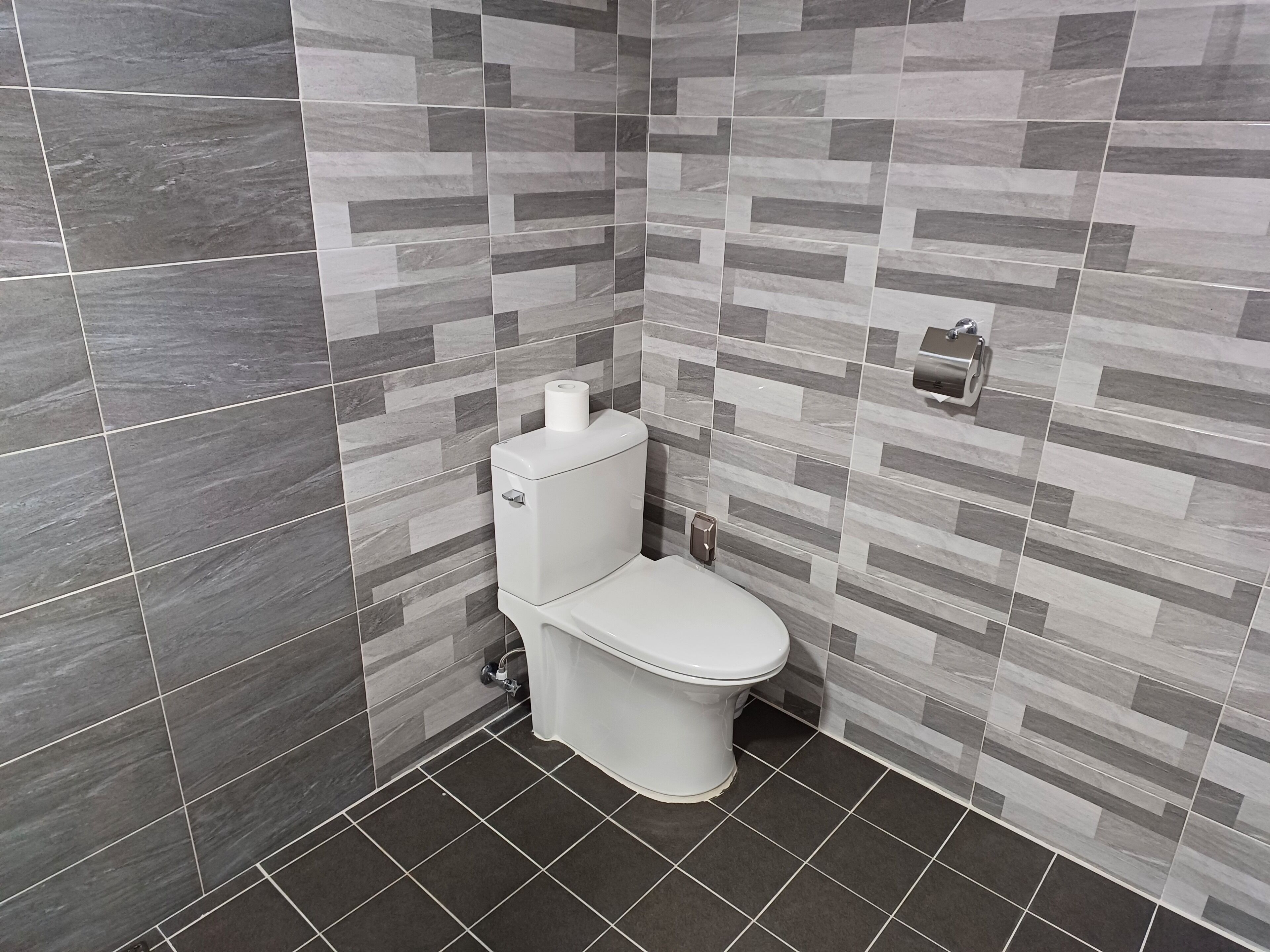 A bathroom with a toilet, a toilet paper holder, and a hand dryer.