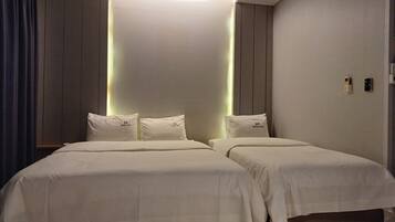 Habitación de hotel con dos camas, diseño moderno e iluminación empotrada.
